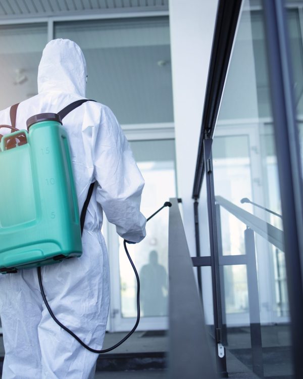 Man with tank reservoir on his back spraying disinfectant to stop corona virus.